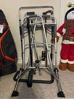 Photo showing an aluminum walker, four canes with different handles and base tips, and a pedal exerciser in front.