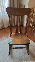 Front view of vintage wooden rocking chair showing carved top rail and turned spindles