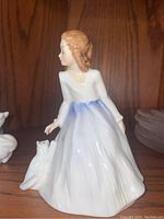Front side profile of the Royal Doulton Andrea figurine with the cat seated at her side, showing the detailed dress and hairstyle.