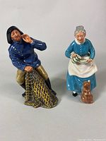Front view of both Royal Doulton figurines showing the fisherman and elderly woman with cat