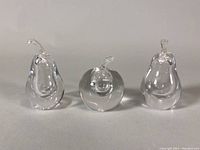Front view of three crystal pear-shaped perfume bottles, showing clear glass, organic shapes, and stems; bottles arranged left to right with varying width.