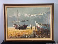 Front view of framed oil on canvas showing two boats on beach with figures
