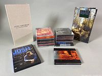 Overview photo of all items including signed Josh Groban CD cover, multiple Josh Groban CDs and DVD, John Denver 4-CD set booklet and Josh Groban 'Illuminations' box.
