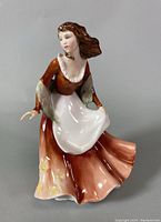 Front view of the Royal Doulton Autumntime porcelain figurine displaying detailed facial features, dress colors and apron.