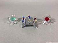 Lot showing two clear crystal daisies with colored centers and a curved stand with clusters of miniature roses.