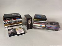 Three stacks of music CDs and a boxed set arranged on a neutral surface, showing spines and covers with vintage classic rock and other music titles.