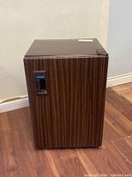 Front view of the closed Danby bar fridge showing wood grain finish and handle with Danby logo.