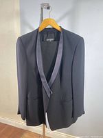 Full view of black tailored blazer with satin shawl lapel, showing its classic style and single button closure.