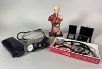 Photo of vintage medical tools including blood pressure cuff, stethoscope, and anatomical model.