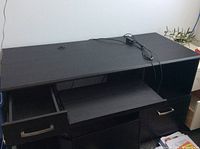 Full view of the black computer desk showing top surface, slide-out keyboard drawer, and left and right drawers open.
