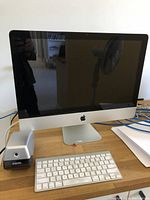 Front view of Apple iMac desktop powered off with wireless keyboard and X-ACTO sharpener on desk.