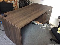 Full view of dark brown wooden desk with two drawers on the right side and cable passthrough hole on top left corner.