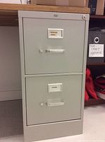 Photo of light grey metal filing cabinet with two labeled drawers 'Marketing Promo' and 'Chaos'.
