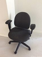 Front view of dark grey office chair showing padded seat, backrest, adjustable armrests, and five-legged wheeled base.