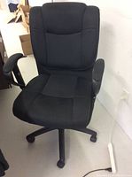 Front view of a black cushioned high-backed office chair showing seat, armrests, and backrest.
