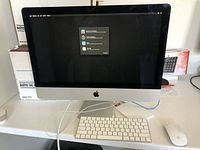 Front view of Apple iMac with Magic Keyboard and Magic Mouse placed in front, showing factory reset screen