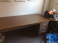 Wide view of the old office desk showing the wood laminate tabletop and side metal drawers under the desk.