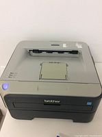 Top view of Brother HL-2140 laser printer showing paper output area, control panel and Brother logo.