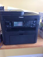 Front view of Canon ImageClass MF21bn showing control panel, numeric keypad, and paper tray.