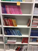 White seven-tier bookshelf filled partially with colorful books arranged by color, showing overall design and shelf structure.