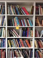 Full view of the white bookshelf filled with various books arranged on each of the seven shelves.