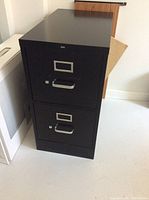 Photo showing one of the two black metal filing cabinets with two drawers, metal handles, and label holders.