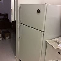 Side view of large white Westinghouse refrigerator with top freezer door and bottom fridge door.
