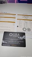 GRA certification documents with grading report details and warranty card showing the authenticity and grading of the 1 carat moissanite.