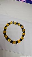 Photo of the stretchy bracelet composed of polished golden Baltic amber beads and alternating matte black onyx beads, laid flat on a surface.