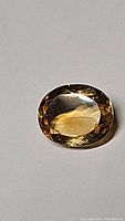 Close-up photo of the 2.59ct oval cut deep golden citrine gemstone showing its clarity and faceting.