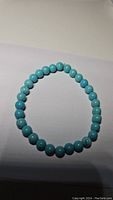 Photo of a stretchy bracelet composed of round robin's egg blue turquoise beads on a white background.