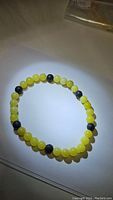 Photo of stretchy bracelet made of round lemon jade beads alternating with black lavastone beads on elastic band.