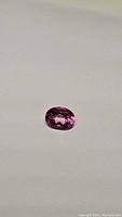 Oval cut natural hot pink topaz gemstone shown on a plain white background to highlight clarity and color.