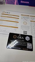 GRA certificate card with gemstone grading details showing heart cut, 1.0 carat weight, D color, VVS1 clarity, and excellent cut quality.