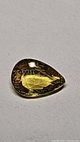 Close-up view of pear cut yellow sapphire gemstone on a white background