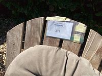 Close-up of teak chair back slats with grey cushion and MaxSold tag taped to top slat