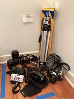 Overview of lot showing multiple cameras, tripod in box, and Tamrac camera bag