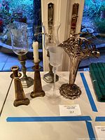 Entire set of silver, crystal, gold plated candle holders and silver flower vase displayed on table.