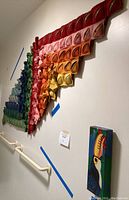 Colorful rainbow cloth art hanging on wall with visible cloth folds and rainbow colors