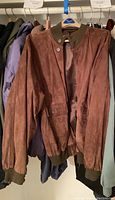 Brown suede-like men's jacket hung on rack