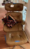 Front view of light brown leather lounge chair and ottoman with decorative pillow
