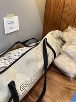 White carrying case labeled 'Stowaway' containing thick braided rope hammock.