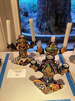 Three hand-painted Spanish style ceramic candelabras set on table under natural light, showing their colorful patterns and candle holders.