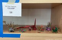 Shelf displaying an array of small colorful wood animal figurines, including spiked creatures, lizards, birds, and abstract shapes.