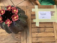 Close-up of teak side table surface with ceramic flowering dessert cactus on top and MaxSold label taped to the table.