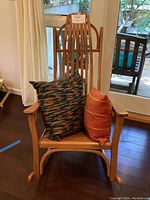 Front view of wooden rocking chair with two diverse decorative pillows placed on seat