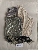 Three pieces including sequinned party dress and two shawls arranged flat on a surface.