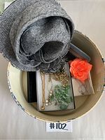 Photo showing the grey fabric hat, hat box, floral accessory, and several costume jewelry pieces inside the hat box.