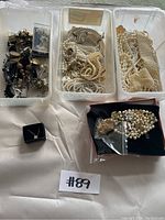 Full overview of jewelry in plastic trays showing various pearl necklaces and bracelets plus one jewelry box with pendant.