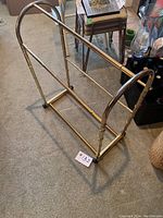 Full view of gold-colored bamboo style towel rack on carpet, includes wheels and label #132 visible on floor.